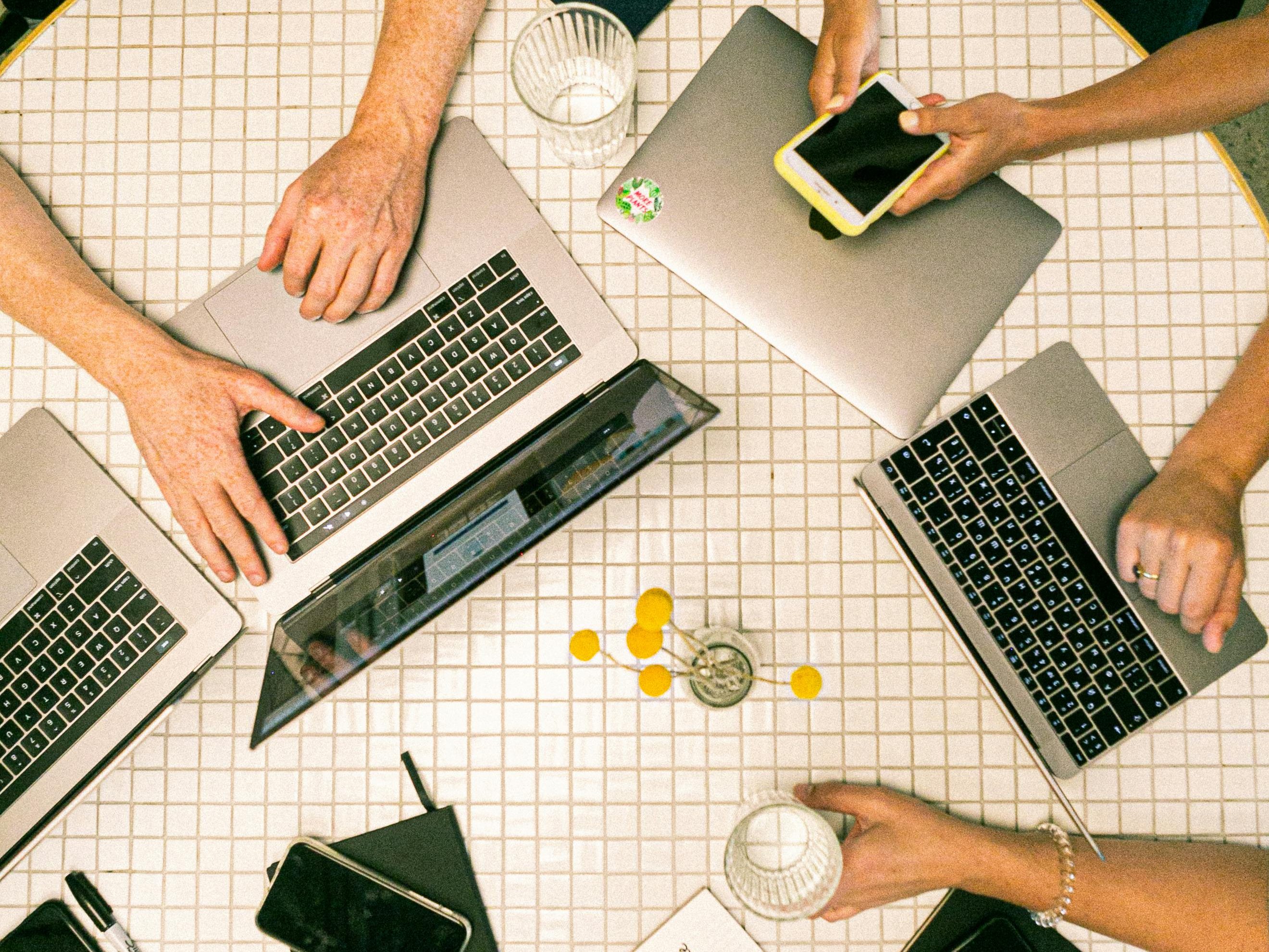 Tisch mit Laptops in einer Besprechung mit mehreren Personen
